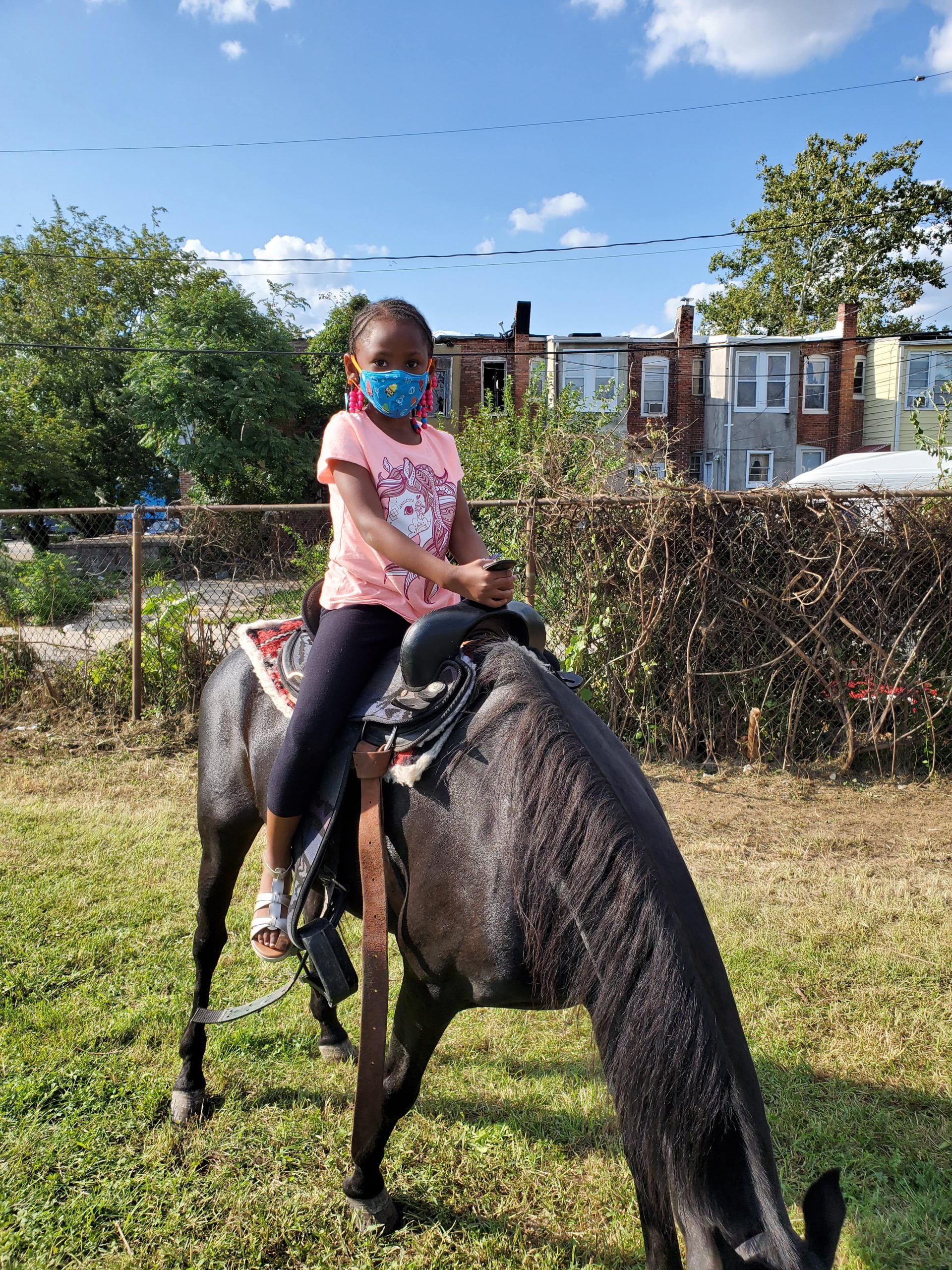 Girl Riding a horse in park heights with a mask